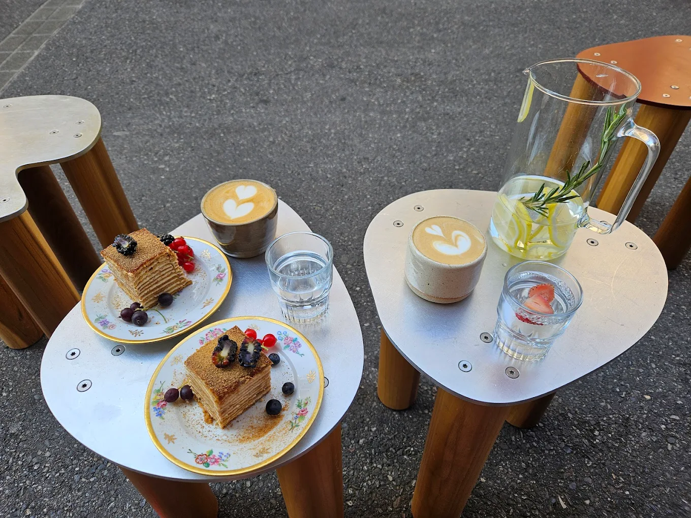 Parts de medovik, le gâteau au miel, avec des cafés latte et une limonade maison sur les tabourets en bois de la terrasse de Sublime Coffee, Genève.