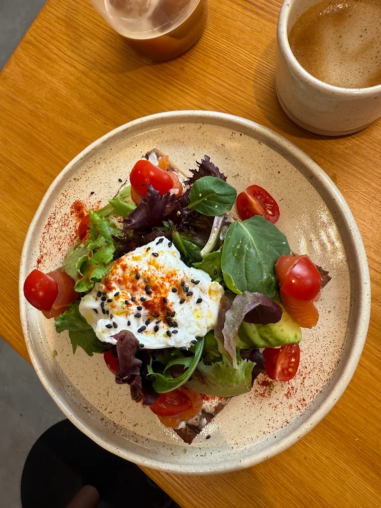 Tartine d'avocat surmontée d'un œuf, pousses et tomates cerises, avec un café, chez Sublime Coffee à Genève.